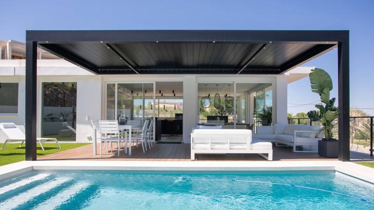 Une élégante pergola bioclimatique s'étend au-dessus d'une terrasse moderne, abritant un espace de vie extérieur parfa...